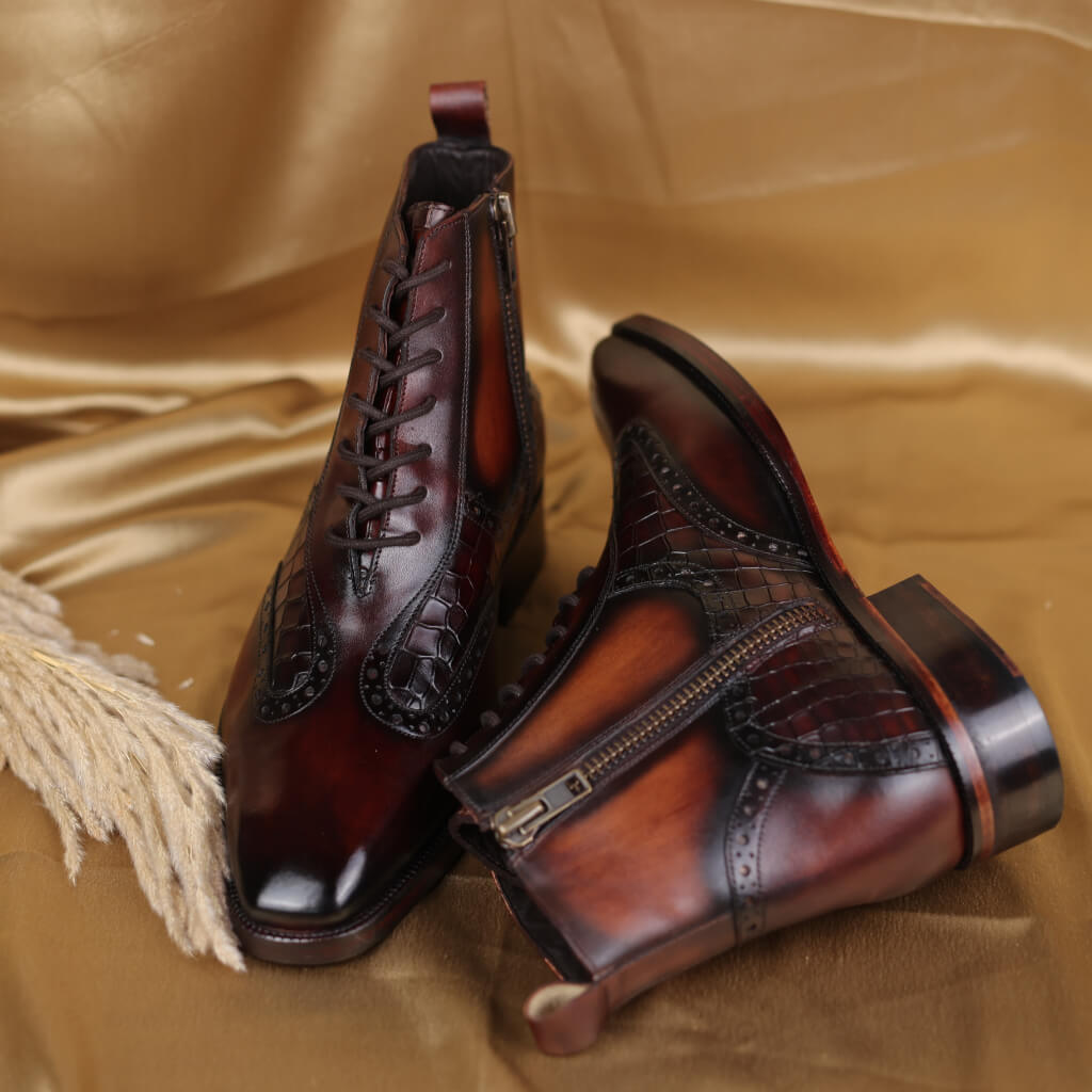 A pair of Plain Toe lace-up boots with a side zipper, crafted with Italian full-grain leather uppers and a hand-built Argentinean leather sole, featuring a rubber protector for better grip. These brown ankle boots showcase a crocodile-style zipper and offer a trendy, durable design that combines authenticity with fashion.