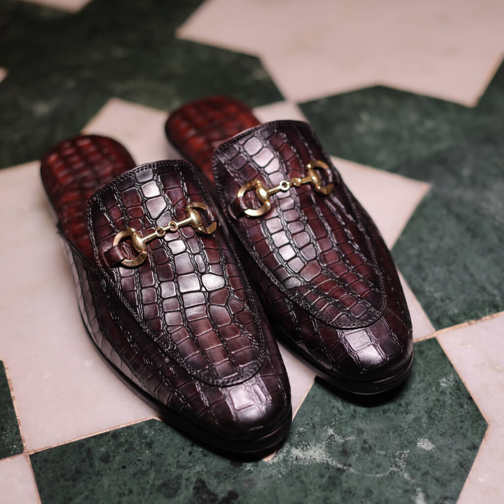 A pair of Hale Luxury Horsebit Slippers by Mille Dollari, featuring a meticulously embossed design that adds texture and distinction. The slippers have an Italian leather sole, ensuring maximum comfort and a luxurious feel with every step. Perfect for both going out and staying in, these slippers elevate your style and make a statement of elegance and comfort.
