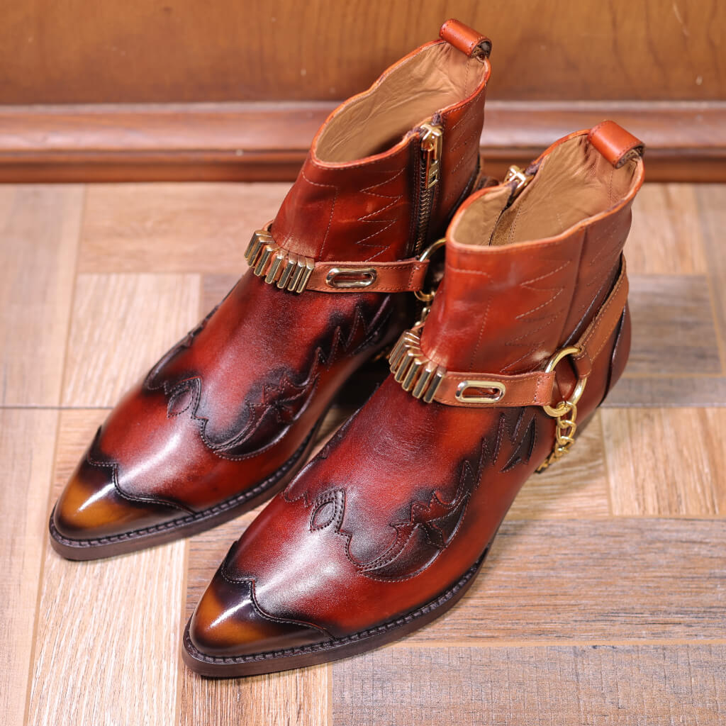 A pair of Rustic Frontier Cowboy Boots featuring a 30mm Cuban heel, intricate laser cut patterns, and perforations. The boots offer a side zipper for easy access and come in two unique finishes: a sleek patent patina or a rugged wooden patina, blending classic cowboy style with modern design.