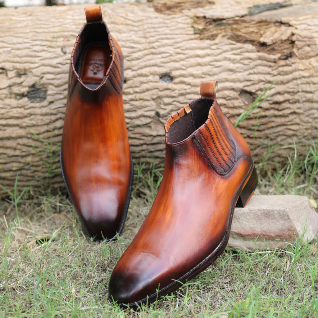 A pair of Imperium Chelsea Boots in Cognac Leather, crafted from premium white crust leather with a hand-finished rich patina for a unique look. The boots feature an Italian leather sole, offering durability and elegance, epitomizing refined craftsmanship.