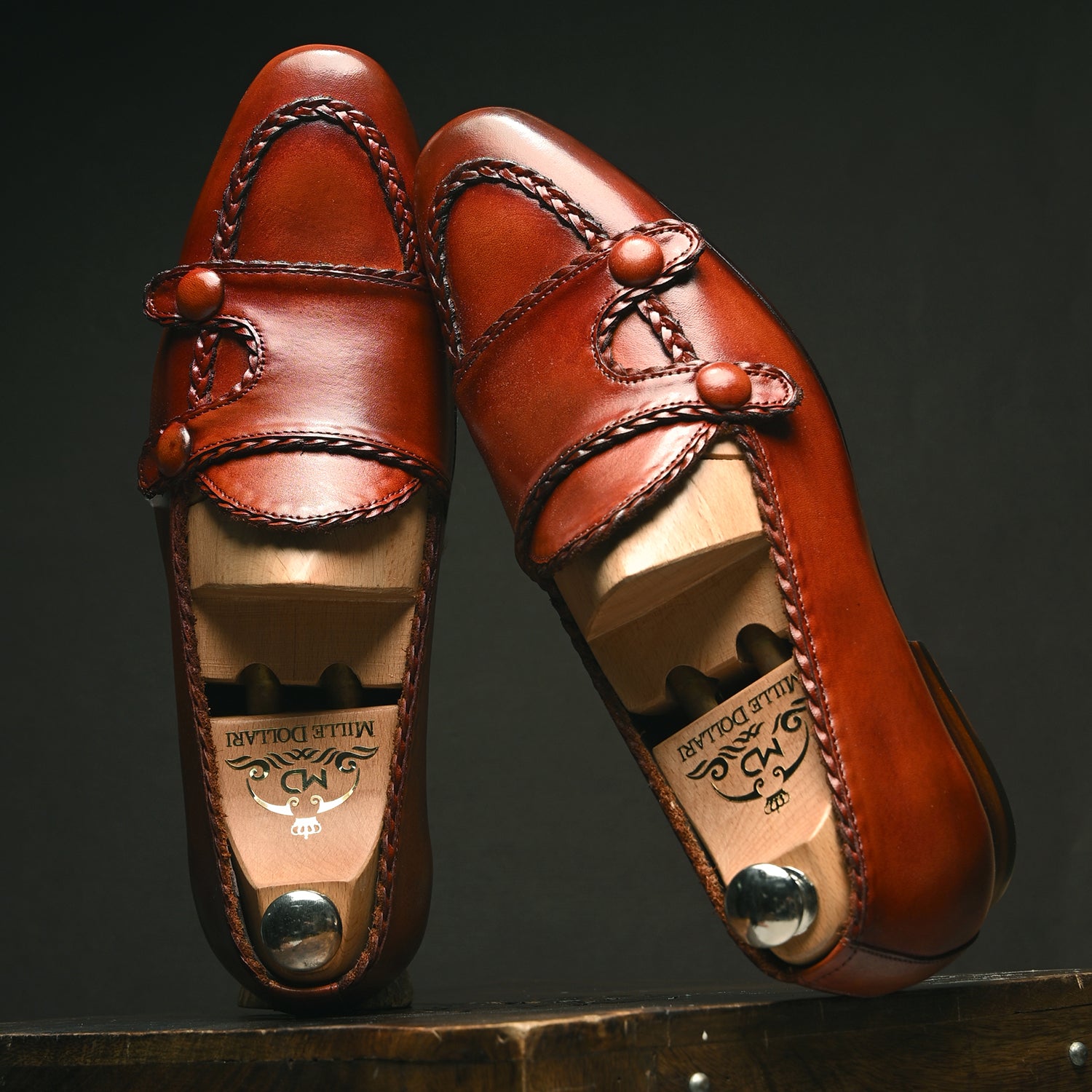 Handcrafted men’s brown leather loafers with patina finish, braided stitching, and vintage button detailing