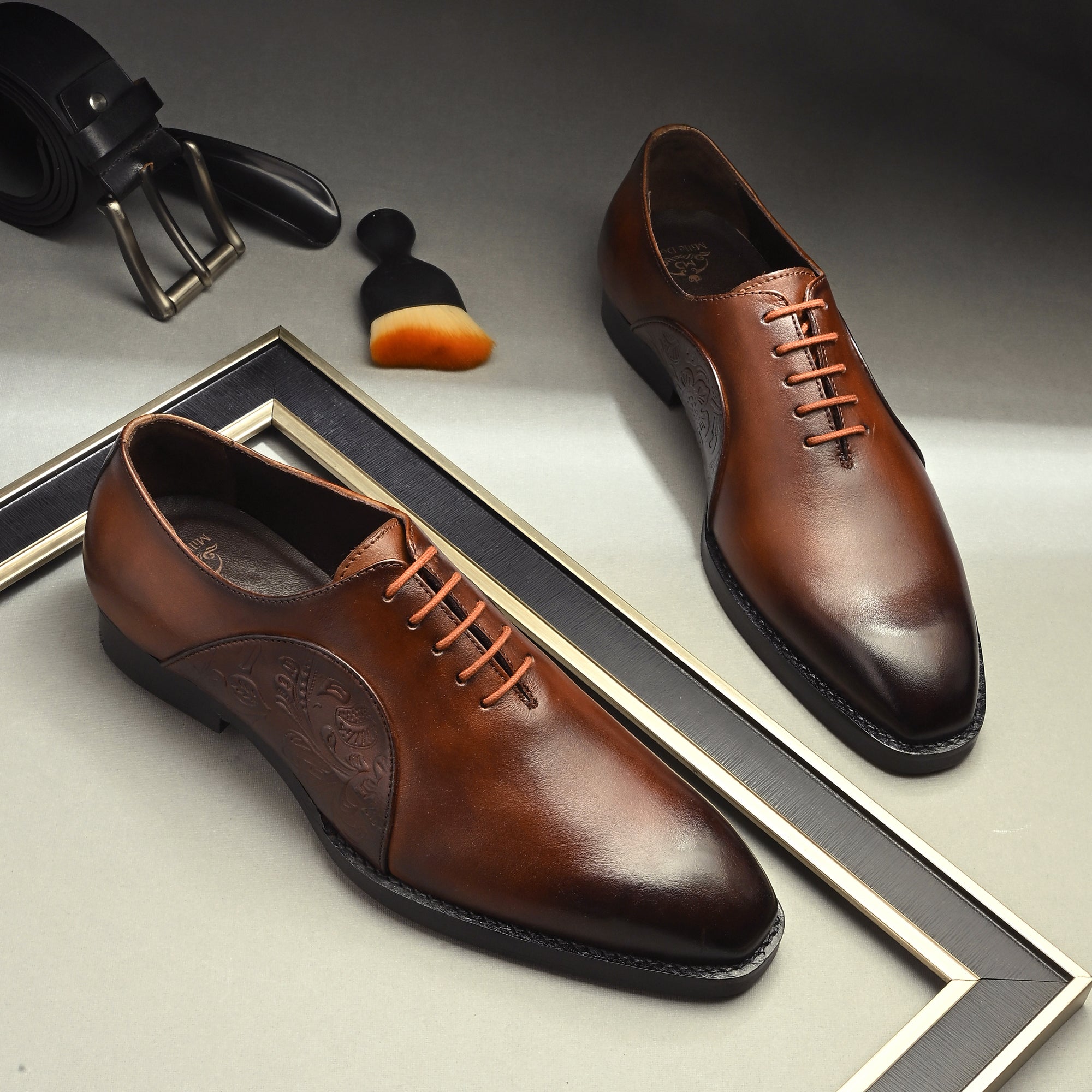 Luxury Mille Dollari handcrafted brown burnished leather Oxford shoes with embossed side design placed in a premium studio setup.