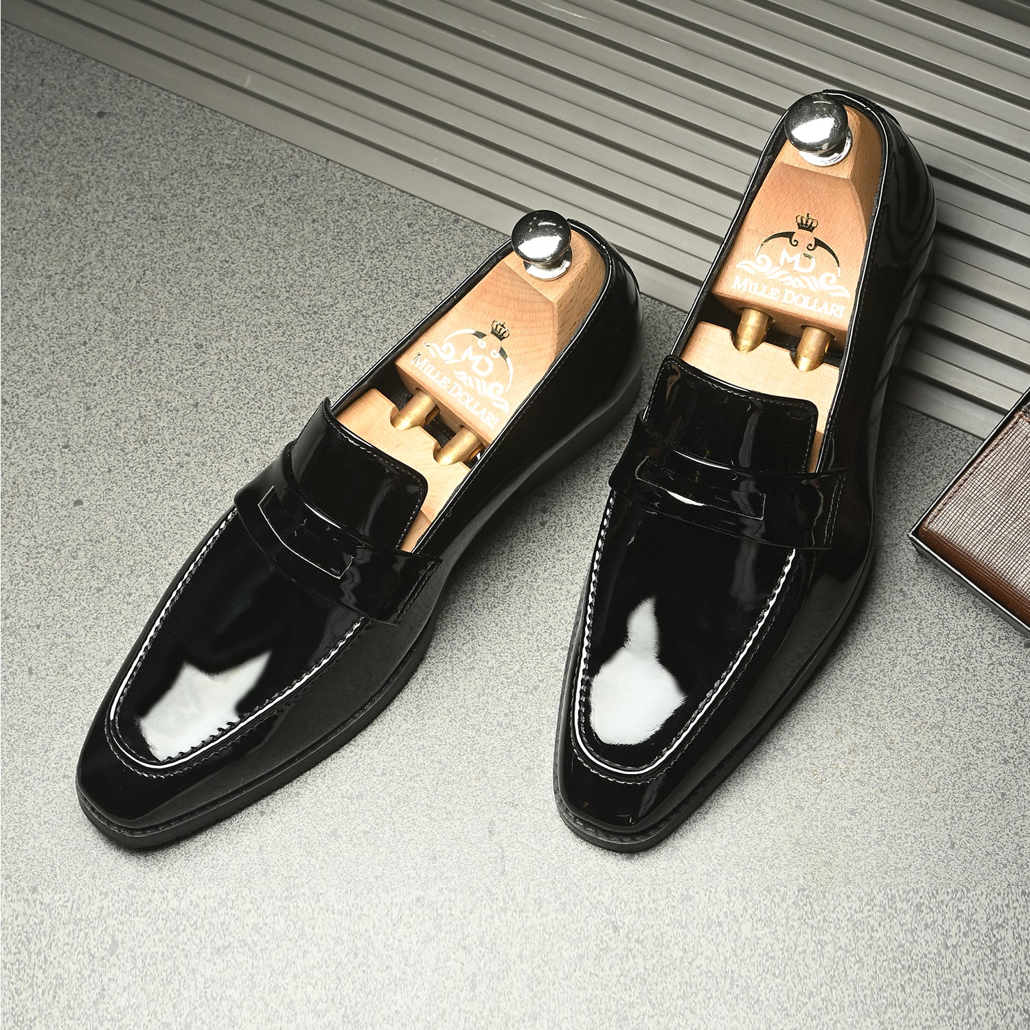 Black patent leather men’s penny loafers with classic saddle strap.
