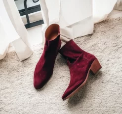 A pair of burgundy suede leather Fiorina slip-on boots for men, featuring a sleek pointed-toe design and a convenient side zipper. These boots, part of the AW24 collection, exude sophistication with their rich suede texture and premium craftsmanship, ideal for elevating formal or casual looks.