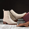 cream suede ankle boots with a leather sole, featuring a sleek design and zipper closure.